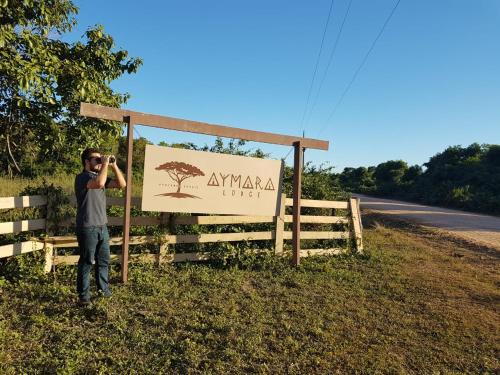 um homem a tirar uma fotografia em frente a um cartaz em Aymara Lodge em Poconé