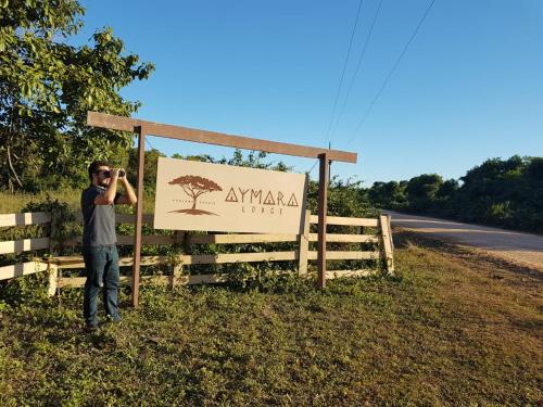 a man taking a picture in front of a sign at Aymara Lodge in Poconé