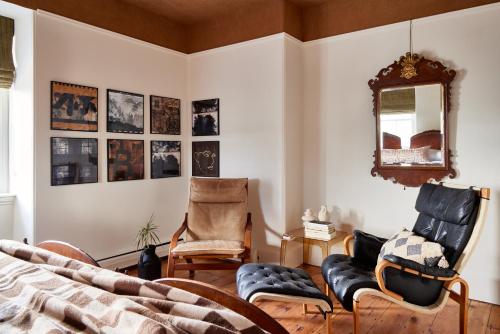 a bedroom with two chairs and a bed and a mirror at Blind Tiger Portland - Carleton Street Guest House in Portland
