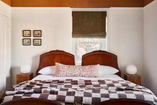 a bed with a checkered blanket and a window at Blind Tiger Portland - Carleton Street Guest House in Portland