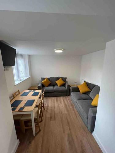 a living room with a couch and a table at Newly built 2 bed flat in the heart of Leek in Leek