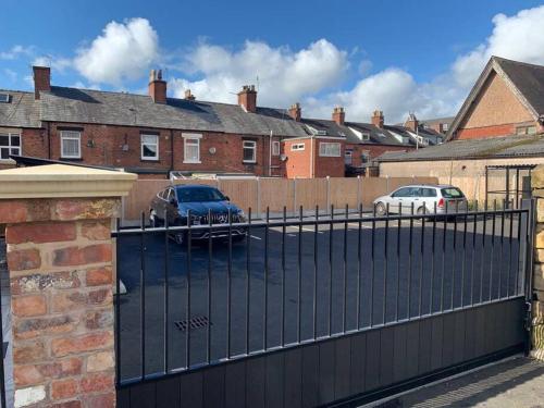 a black fence with cars parked in a parking lot at Newly built 2 bed flat in the heart of Leek in Leek