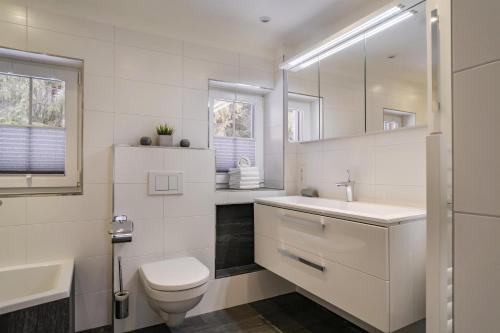 a white bathroom with a toilet and a sink at Haus Bambi in Achenkirch