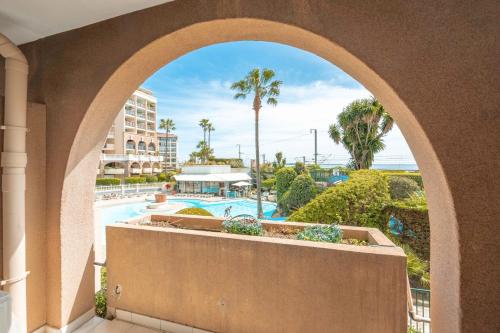 - une vue sur la piscine depuis une arche d'un complexe dans l'établissement Résidence Pierre & Vacances Cannes Verrerie, à Cannes