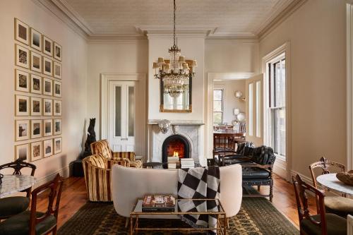 a living room with a fireplace and a table and chairs at Blind Tiger Portland - Carleton Street Guest House in Portland