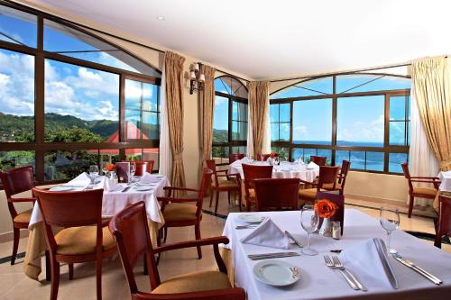 a restaurant with white tables and chairs and windows at Eurostars Grand Cayacoa in Santa Bárbara de Samaná