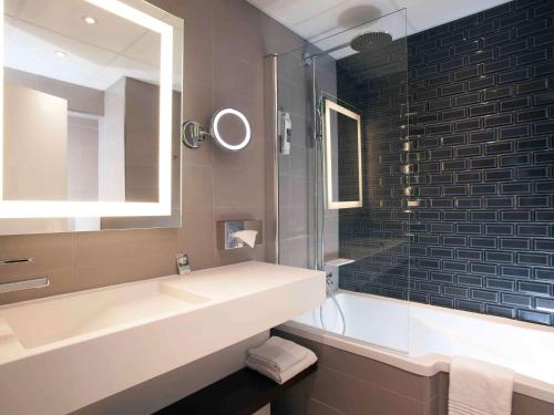 bagno con lavandino e specchio di Mercure Paris Ivry Quai De Seine a Ivry-sur-Seine