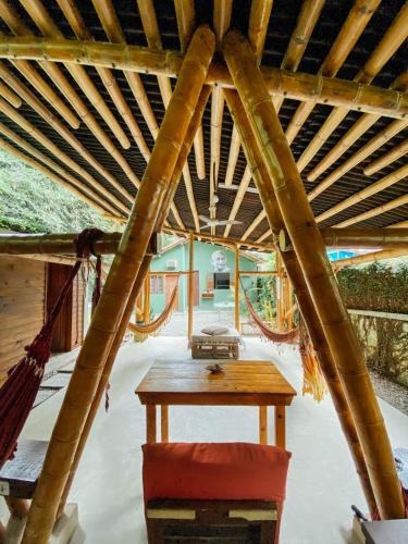 a wooden room with a table and a hammock at Balaio Hostel Ilha Grande in Abraão