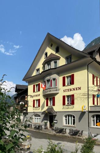 a large yellow building with red shuttered windows at Hotel Sternen in Gurtnellen