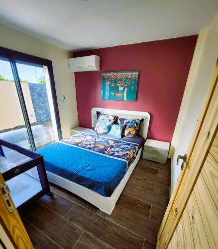 a bedroom with a bed and a red wall at Les Villas Jasmin Standing Piscine Chauffée Jacuzzi 5 Ch 14 Pers in Baie-Mahault