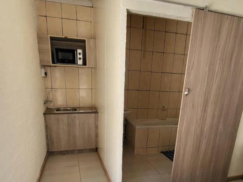 baño pequeño con fregadero y microondas en Hephzibah Guesthouse en Welkom