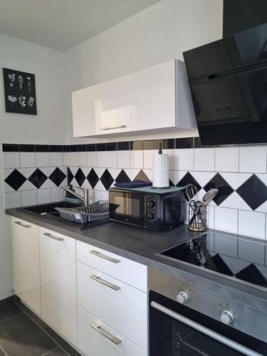 een keuken met witte kasten en zwarte en witte tegels bij Chez peggy in Metz