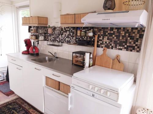 - une cuisine blanche avec évier et cuisinière dans l'établissement Tiny house Schoorl Bergen NH, à Warmenhuizen