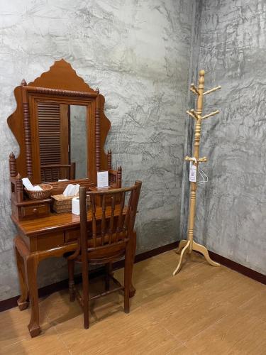 a dressing table with a mirror and a wooden chair at Yaowarate Sport Club and Resort ไร่เยาวเรศ in Ban Mae Ho Phra