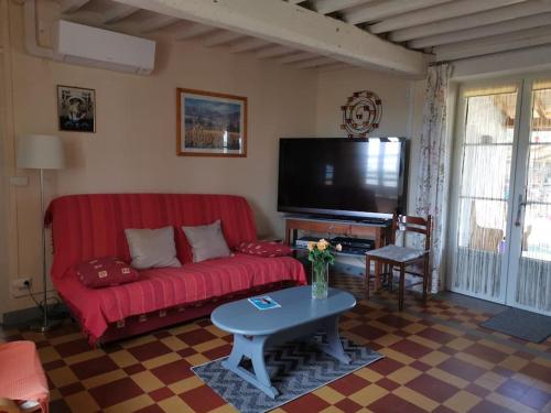 - un salon avec un canapé rouge et une télévision dans l'établissement Gîte familial de charme entier en Gascogne, à Marseillan
