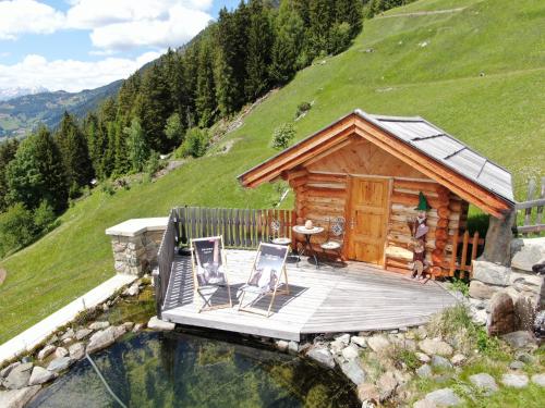 a log cabin with a deck and a table and chairs at Wiesenhof in Kaunerberg