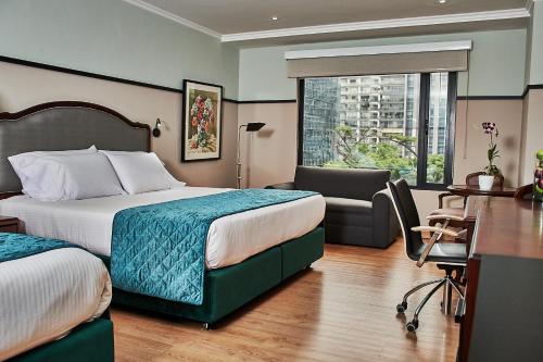 Habitación de hotel con 2 camas y escritorio en Hotel Poblado Plaza en Medellín