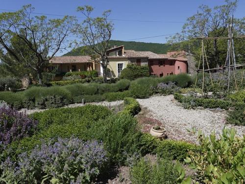 un patio con una casa y un jardín con flores en La Palombe, en Octon