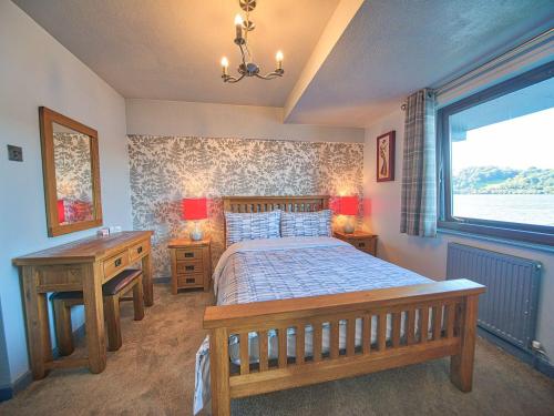 a bedroom with a wooden bed and a window at Drysgol Lakeside - Bala Lake in Bala