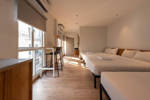 a hotel room with three beds and a bar at Boxpackers Pratunam in Bangkok
