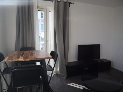 een woonkamer met een tafel en een televisie bij Appartement entier avec parking gratuit proche de Paris et Aéroport d'Orly in Thiais