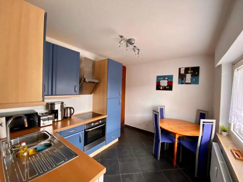a kitchen with blue cabinets and a wooden table at Lounge - Gemütliche Ferienwohnung am Asreg, Bad Zwischenahn in Bad Zwischenahn