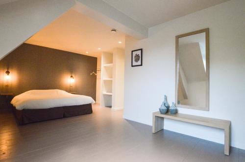 Schlafzimmer mit einem Bett, einem Spiegel und einer Bank in der Unterkunft Vakantiewoning De Papaver in Kemmel