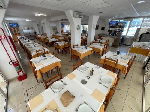 an empty restaurant with white tables and wooden chairs at Albergo Désirée in Alba Adriatica