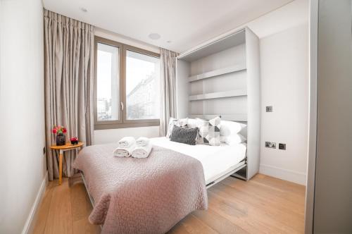 1 dormitorio con 1 cama con 2 toallas en Stunning Modern Apartment close to Hyde Park by UnderTheDoormat, en Londres