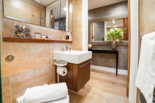 bagno con lavandino e specchio di Stunning Modern Apartment close to Hyde Park by UnderTheDoormat a Londra
