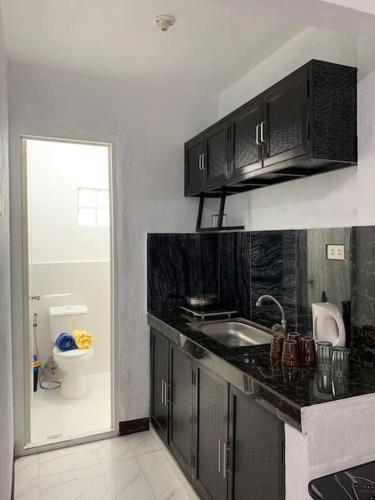 una cucina con armadi neri, lavandino e servizi igienici di REMMs PLACE Aircondition unit A a Kay Riapay