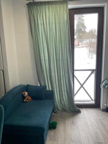 a teddy bear sitting on a blue couch in front of a window at Bakuriani mix appartment in Bakuriani