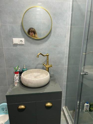 a bathroom with a sink and a woman in a mirror at Bakuriani mix appartment in Bakuriani