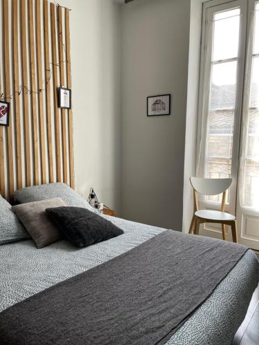 une chambre avec un lit, une chaise et une fenêtre dans l'établissement Le charmant quai bourgeois, à Bordeaux