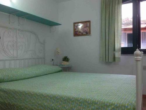 Un dormitorio con una cama con sábanas verdes y una ventana en Holiday in Sardinia, en Santa María