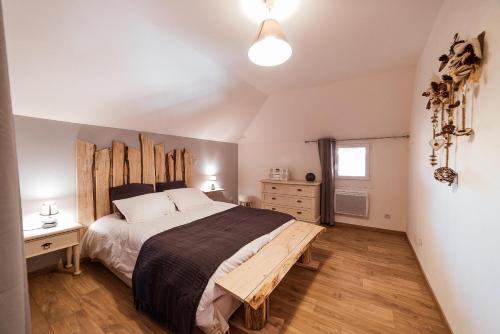 een slaapkamer met een groot bed met een houten hoofdeinde bij Logements calmes avec piscine, jardin et parking in Buchères