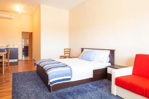 a bedroom with a bed and a red chair at Apartments Facini in Košljun