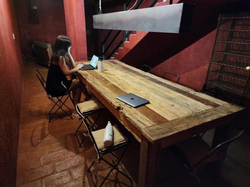 een vrouw aan een houten tafel met een laptop bij Casa Lopez in Chacras de Coria