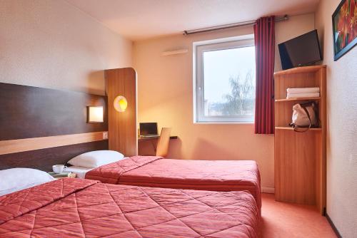 a hotel room with two beds and a window at Premiere Classe Le Mans Ouest Universite in Le Mans