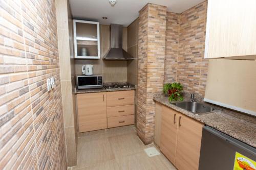 a kitchen with a sink and a brick wall at Roots Hotel Apartment in Accra