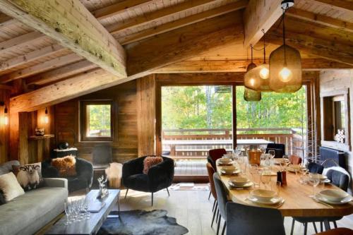 ein Wohnzimmer mit einem Tisch und Stühlen sowie einem großen Fenster in der Unterkunft Chalet de luxe sur les pistes - 5 chambres in Combloux
