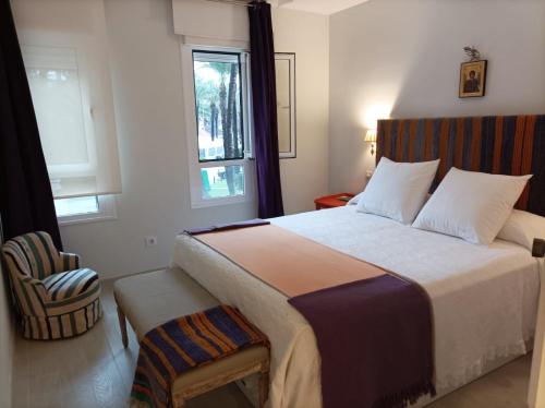 1 dormitorio con 1 cama con ventana y silla en Sotogrande Paseo del Rio, en Sotogrande