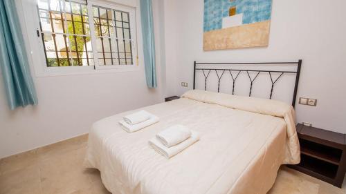 a bedroom with a white bed with two towels on it at Residencial Duquesa Ground Floor Apartment in San Luis de Sabinillas