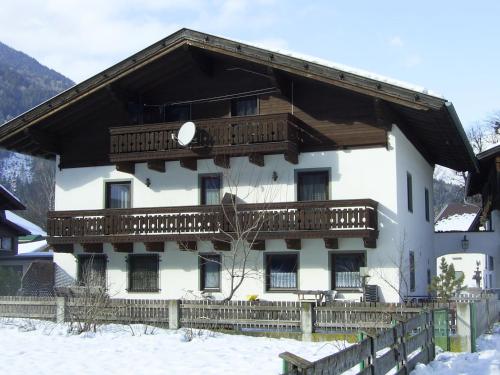 a large white building with wooden balconies in the snow at Privatzimmer Bundschuh in Amlach