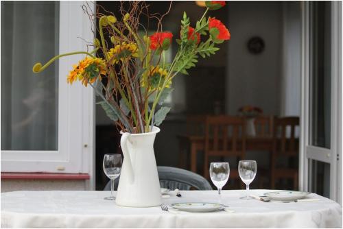 a white vase with flowers on a table with glasses at Agroturystyka Lisa Młyn in Najmowo