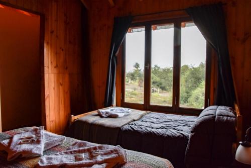 2 Betten in einem Zimmer mit Fenster in der Unterkunft Cabaña El Maqui in San Martín de los Andes