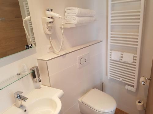 a white bathroom with a toilet and a sink at Les Chants d'Ailes - Hôtel Face Mer in La Turballe