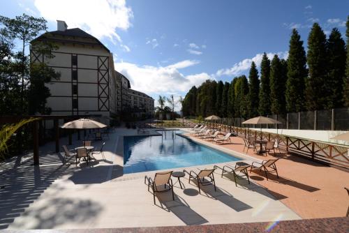 - une piscine avec des chaises et des parasols à côté d'un bâtiment dans l'établissement Vista Azul Apart Hotel - Vista Pedra Azul, à Domingos Martins