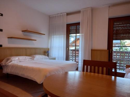 a bedroom with a bed and a table and windows at Residence Biancaneve in Aprica