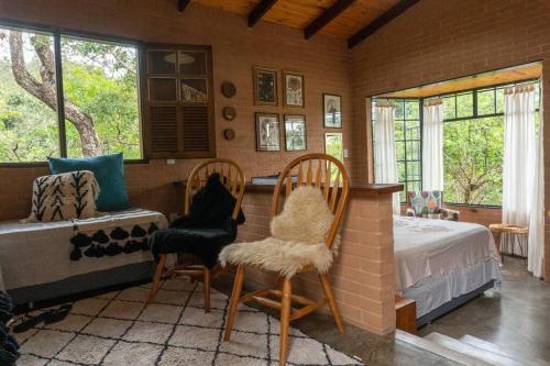 1 dormitorio con 1 cama, 2 sillas y ventanas en Segredo dos Pireneus en Pirenópolis